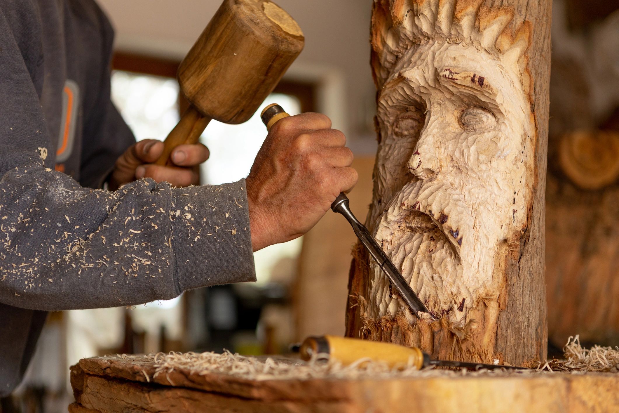 Artist carving wood by hand with mallet and chisel